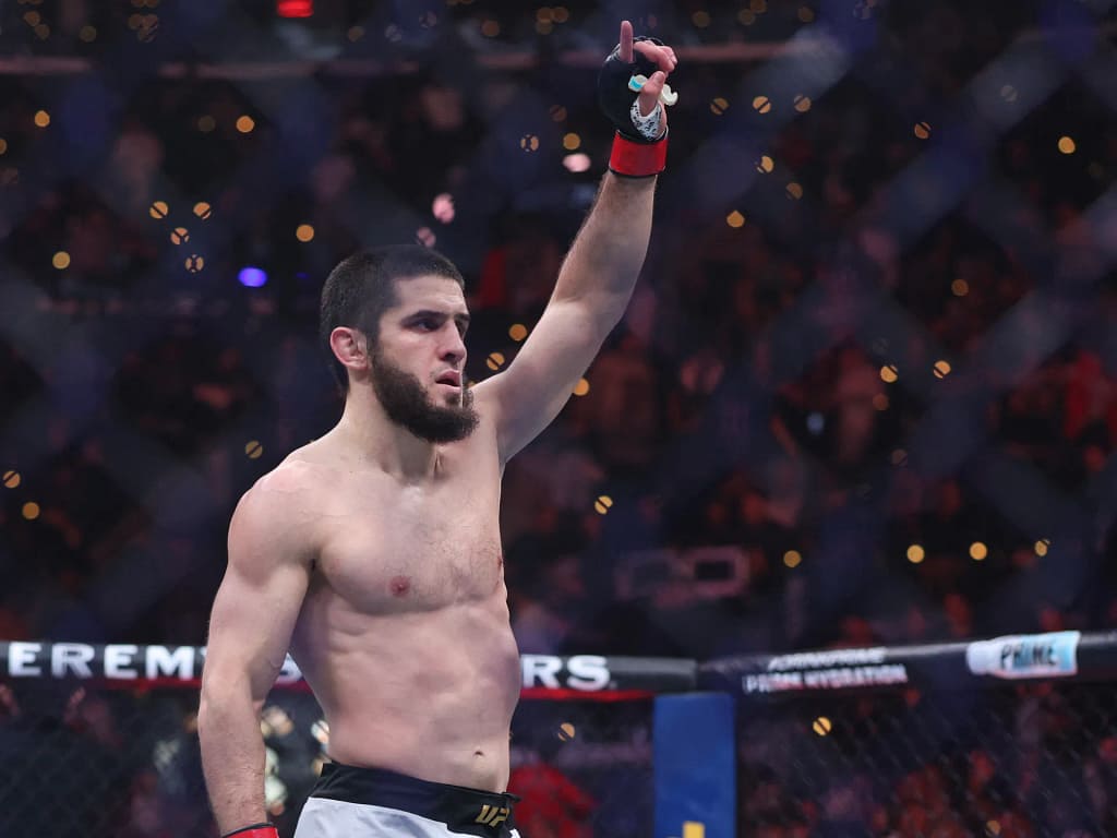 A picture of Islam Makhachev raising his hand after winning